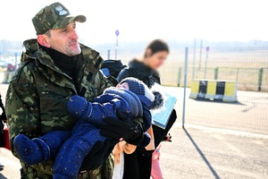 Medyka, marzec 2022. Ewakuacja uchodźców z Ukrainy. Funkcjonariusz SG pomaga matce z dzieckiem (fot. Darek Delmanowicz) 